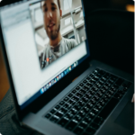 A person on a laptop video call, showing a man partially visible on screen