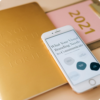 A smartphone displaying a branding guide rests on a gold notebook