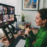A woman in a green sweater participates in a video call on a desktop monitor